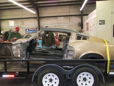1967 Ford Mustang - A 1967 Ford Mustang coupe is seen on a trailer, with its doors removed, in a workshop setting.