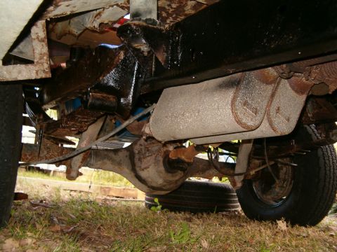 1979 Ford Bronco - The undercarriage of an older vehicle reveals its suspension and exhaust components, with a spare tire resting below.