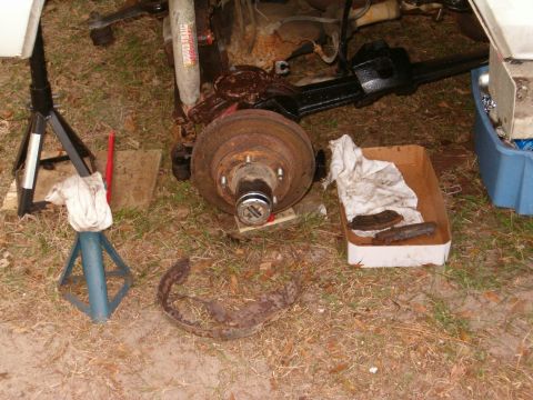 1979 Ford Bronco - Vehicle axle and brake components are laid out on the ground, suggesting maintenance or repair work.