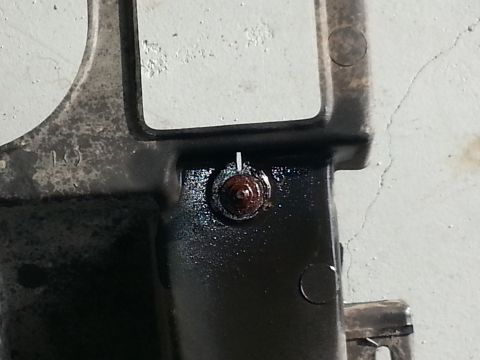 1994 Ford Bronco - This image shows a close-up of a vehicle part, likely from a headlight assembly, with a rusty bolt and some oil residue.