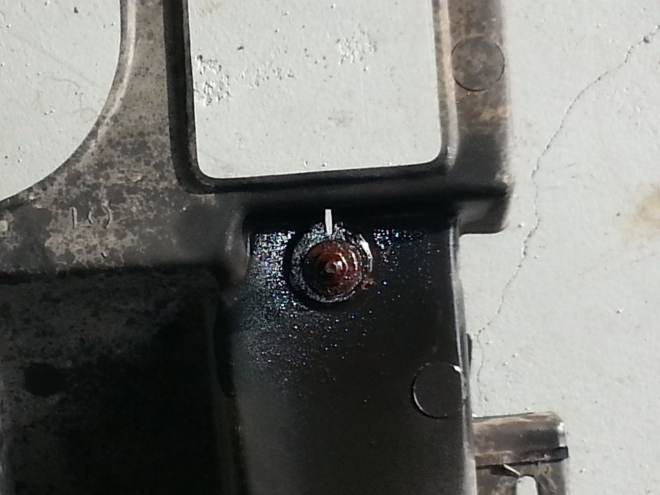 Close-up of a rusty bolt on a black vehicle part