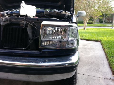 1994 Ford Bronco - Close-up of a black Ford F-Series truck headlight assembly, showing chrome trim details.