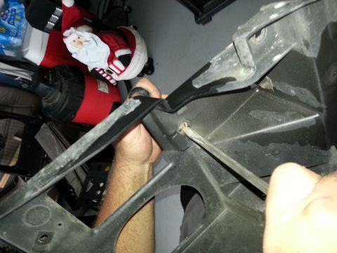 1994 Ford Bronco - A person uses a screwdriver on a black plastic headlight assembly part.