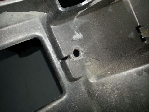 1994 Ford Bronco - Detail of a vehicle's plastic grille, showing a drilled hole and mounting points.