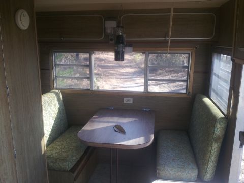 1986 Ford Bronco - Interior view of a camper with seating and a table, looking out two windows.