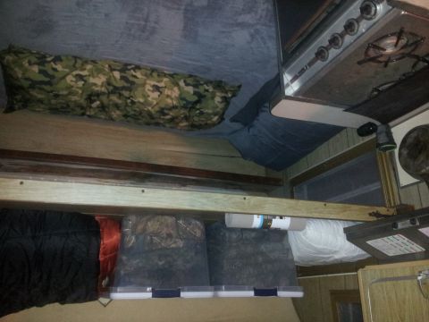 1986 Ford Bronco - The interior of a camper shows sleeping bags, storage bins, and a stove, suggesting a living or recreational space.