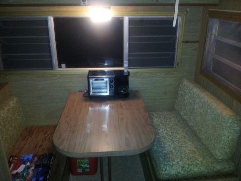 1986 Ford Bronco - The interior of a camper shows a table with bench seating and a toaster oven on the table.