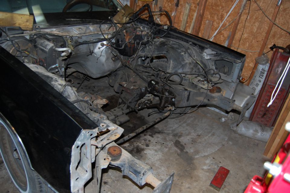 Black car chassis with exposed engine bay and front frame, disassembled
