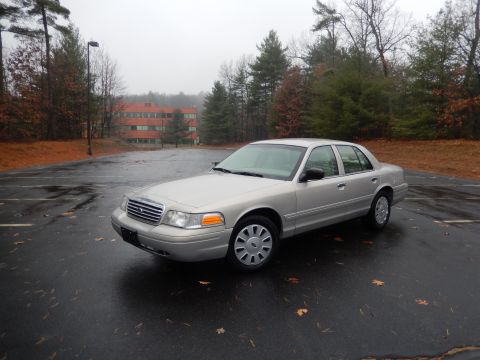 2001 Ford Crown Victoria - Silver 2001 Ford Crown Victoria sedan sits in an empty parking lot on an overcast day.