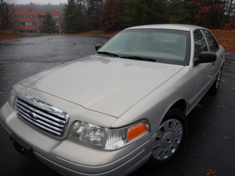 2001 Ford Crown Victoria - Front 3/4 view of a silver 2001 Ford Crown Victoria parked on a wet asphalt lot.