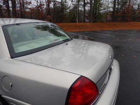 2001 Ford Crown Victoria - Rear view of a silver 2001 Ford Crown Victoria parked in a lot with trees in the background.