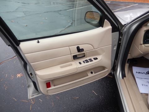 2001 Ford Crown Victoria - The interior door panel of a 2001 Ford Crown Victoria shows beige upholstery and power controls.