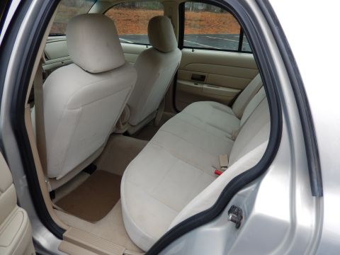 2001 Ford Crown Victoria - The interior of a car shows the rear seats and door panel, with a view of trees outside.