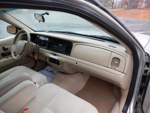2001 Ford Crown Victoria - The interior of the 2001 Ford Crown Victoria features tan upholstery and a beige dashboard with a radio and climate controls.