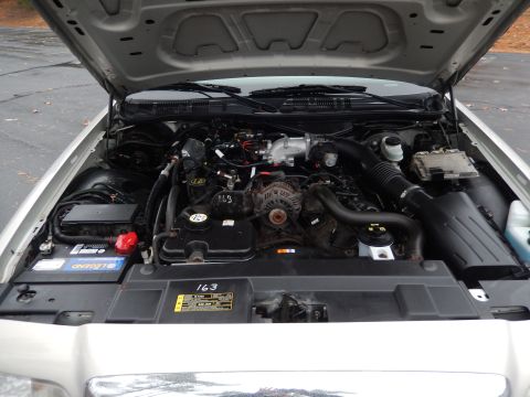 2001 Ford Crown Victoria - The engine bay of a vehicle is shown with the hood open, displaying the engine components and a label indicating unit number 163.