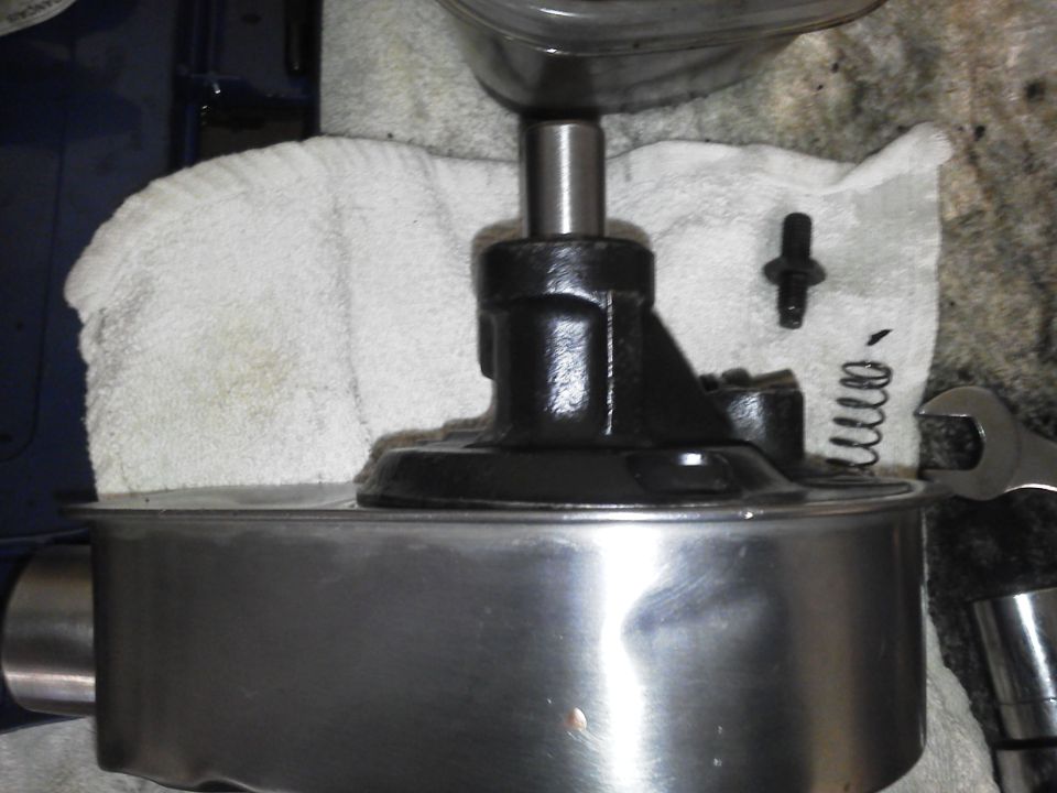 power steering pump assembly on a metal container with a wrench and spring nearby