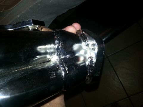 1994 Ford Bronco - A hand holds a chrome exhaust pipe section, showing a bolted flange connection.