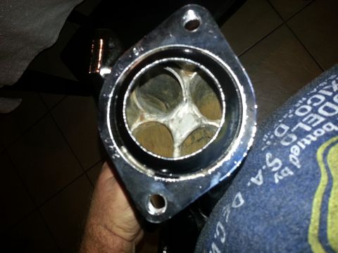 1994 Ford Bronco - Close-up view of an exhaust manifold flange with internal valves, held by a person's hand.