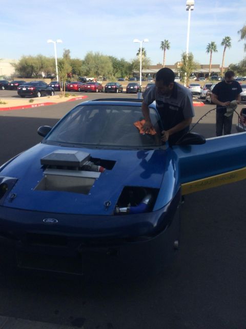 1995 Ford Probe - A person cleans the windshield of a modified blue 1995 Ford Probe in a parking lot.