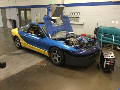 1995 Ford Probe - A modified Ford Probe is shown with its engine exposed and butterfly doors open, hooked up to a charger.