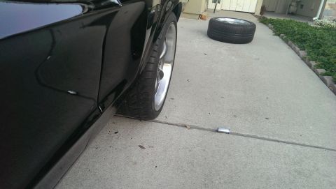 1987 Ford Bronco - Side view of a black vehicle's fender and tire, with a spare tire nearby.