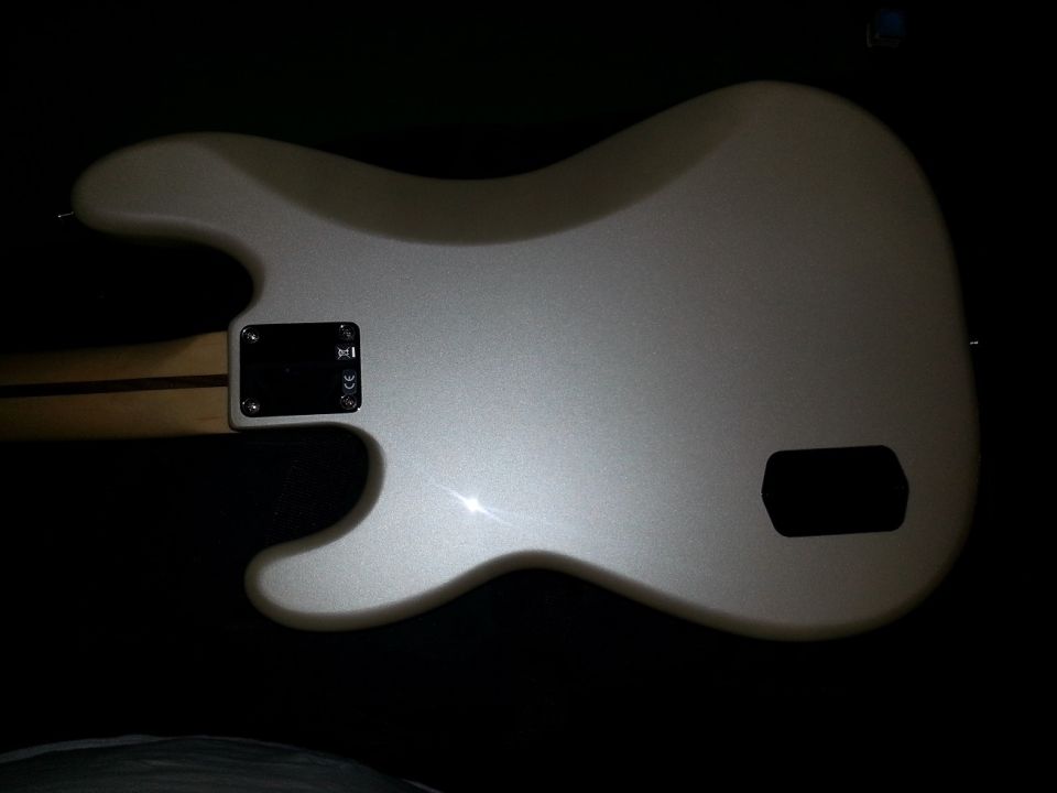 Back of a silver electric bass guitar showing neck joint and control plate