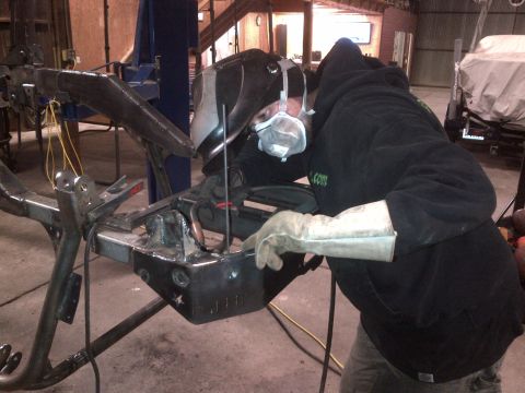 1985 Jeep CJ7 - A person is welding a metal frame in a workshop setting.