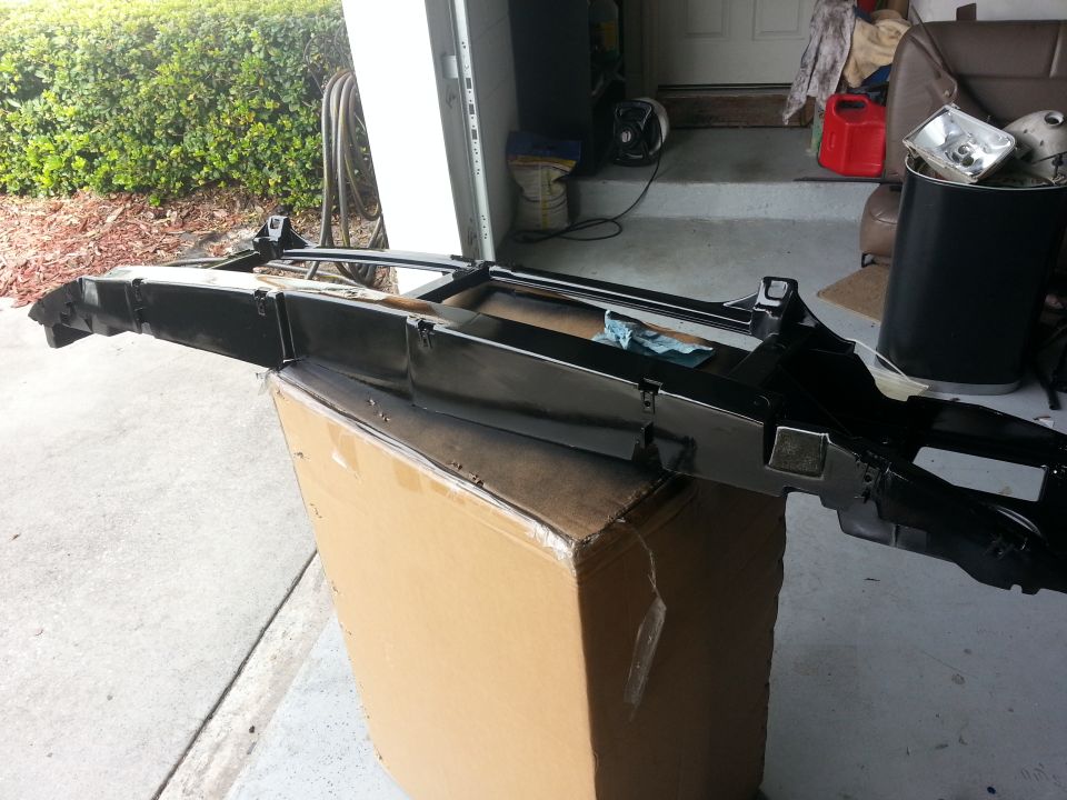 Black automotive part on a cardboard box, with a headlight in the background
