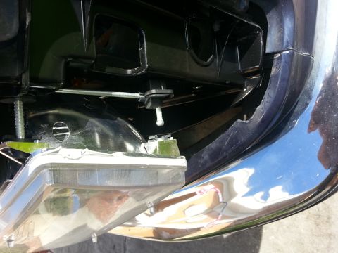 1994 Ford Bronco - The headlight assembly is detached from the vehicle, revealing internal mounting hardware and the chrome bumper.