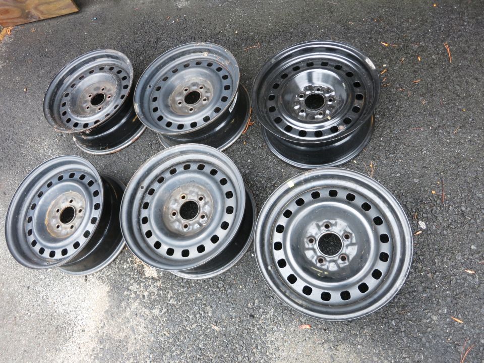 six steel wheels stacked and laid out on asphalt