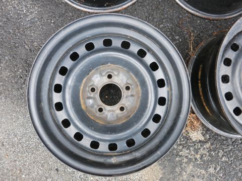2001 Ford Crown Victoria - A single steel wheel rim with multiple square cutouts is shown, with other similar rims visible in the background.