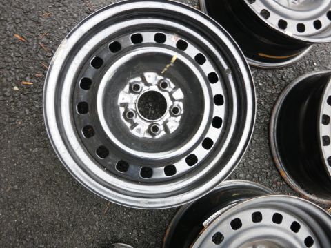 2001 Ford Crown Victoria - Several steel wheels are laid out on asphalt, showing their metallic rims and dark centers.