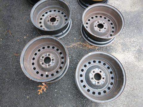 2001 Ford Crown Victoria - A set of four steel wheels, likely from a sedan or SUV, are shown on asphalt.