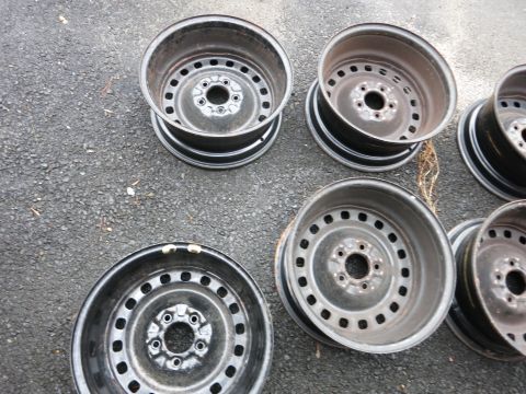 2001 Ford Crown Victoria - Collection of steel wheels, some showing wear and tear, laid out on a dark, textured surface.