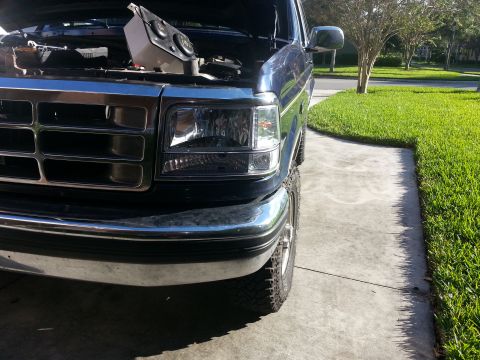 1994 Ford Bronco - Front end of a Ford F-Series truck with the hood open, parked on a driveway.