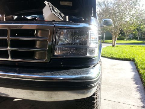1994 Ford Bronco - Close-up of the front grille and headlights of a Ford truck, with the hood raised.