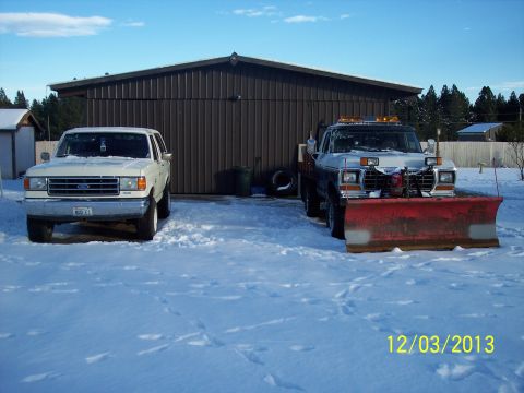 1973 Ford F-250 - Two Ford trucks are parked in a snowy area in front of a building.