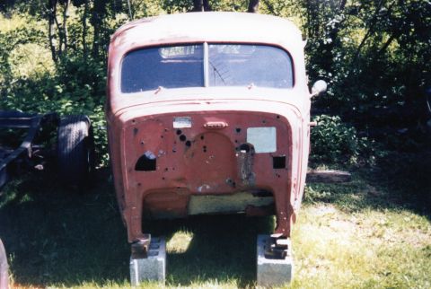 1935 Chevrolet New - This 1937 truck cab is missing its grille and hood, resting on concrete blocks outdoors.