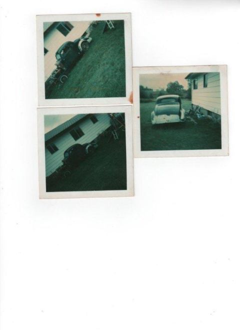 1935 Chevrolet new - A dark sedan is parked on a grassy slope beside a white house.