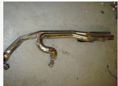 1995 Ford F-150 - A chrome exhaust manifold is shown lying on a concrete surface. The part has two pipes that join together.