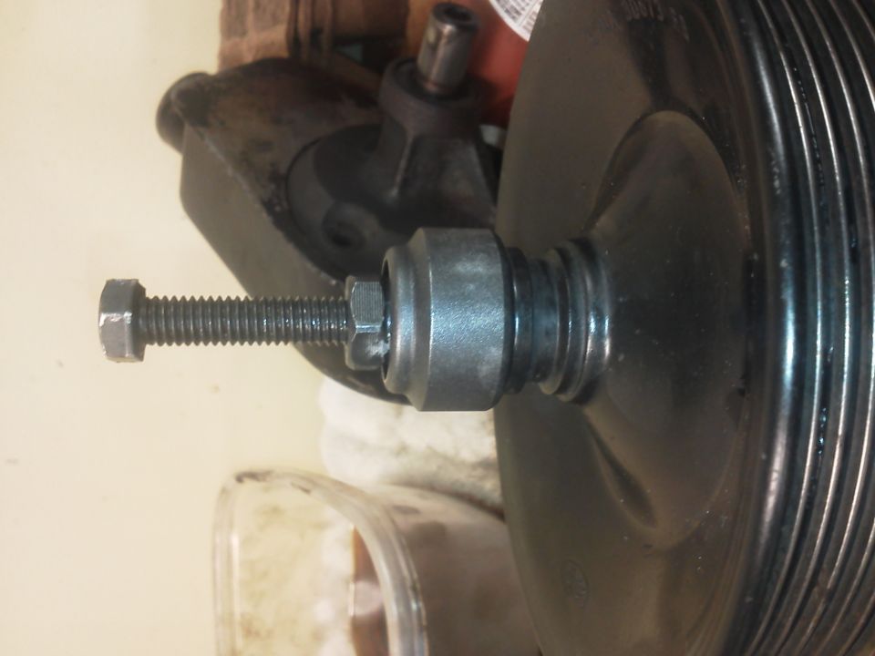 Power steering pump pulley with a bolt and nut threaded into its center