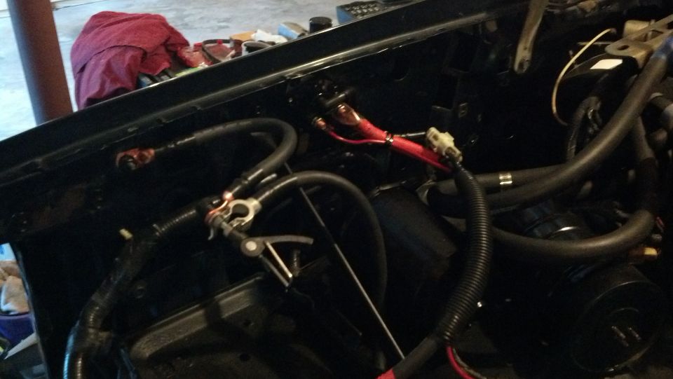 Engine bay with black wiring and red battery cables. A Supermotors.net logo is in the lower right