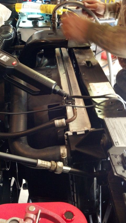 1993 Ford Bronco - Close-up view of a vehicle's engine bay, focusing on the radiator and hoses, with a tool in use.
