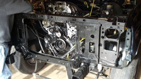 1993 Ford Bronco - The front end of a vehicle is disassembled, showing the engine bay and various mechanical parts during a rebuild.