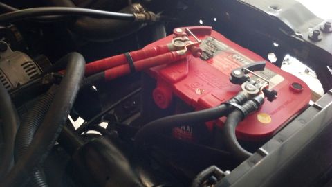 1993 Ford Bronco - Close-up view of a red Optima battery and its terminals within a vehicle's engine compartment.