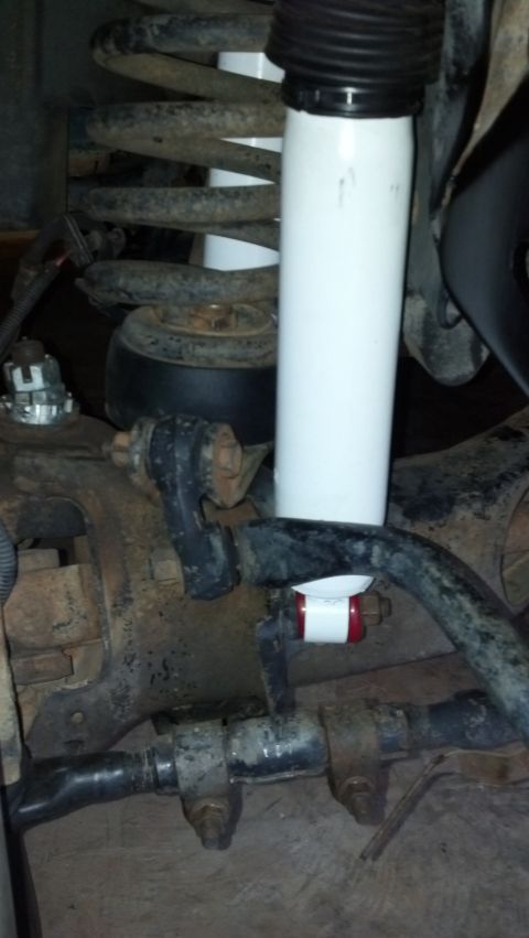 1993 Ford Bronco - Close-up view of suspension components, including a white shock absorber and coil spring, with a red and white stabilizer visible.
