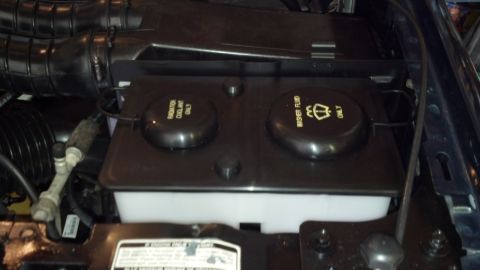 1993 Ford Bronco - Close-up of engine bay fluid reservoirs, showing labels for coolant and washer fluid.