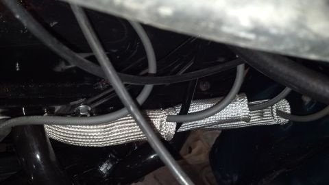 1993 Ford Bronco - Underneath the hood, a tangle of wires and a protective heat shield are visible.