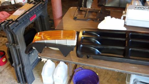 1993 Ford Bronco - Grille and headlight assembly for a Ford Bronco, likely from the early 1990s, laid out on a workbench.