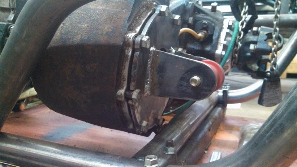 Close-up of a rusty transfer case with an exhaust pipe and metal tubing